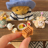 Miniature wooden glass coaster holder shaped like a teddy bear, with tiny bear-face engraved wooden coasters neatly stacked inside. Adorable 1:6 scale dollhouse kitchen accessory for miniature coffee tables, tea parties and collectible miniature home decor by Real Mini World.