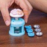 Miniature blue button maker with pink paw-shaped handle and button-making accessories for DIY miniature crafts.