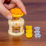 Miniature yellow cat button maker with paw-shaped press and button-making accessories for mini crafting.