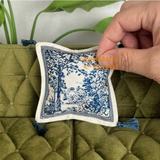 Handcrafted miniature ivory and navy blue toile de Jouy sofa cushion featuring an intricate French countryside garden scene, decorative blue tassel corners and elegant vintage fabric design for luxury dollhouse living room decor by Real Mini World.