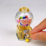 Real functioning translucent yellow miniature chocolate dispenser from RealMiniWorld — palm-sized gumball machine with colorful chocolates and silver twist handle